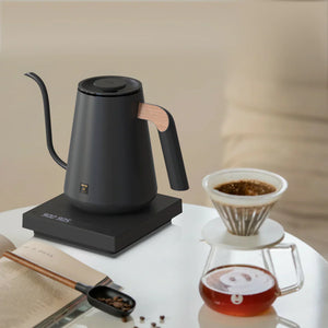 Zwarte elektrische waterkoker met houten detail aan het handvat en smalle tuit voor barista- en filterkoffie-accessoires, alles over koffie.
