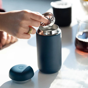 Hand die een filter in een matblauwe herbruikbare koffiebeker plaatst, onderdeel van Take away en EspressoGear, alles over koffie.