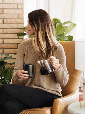 Vrouw in beige trui met barista espresso-serveerkannetje van glas, modern design, Laatste nieuws, alles over koffie.